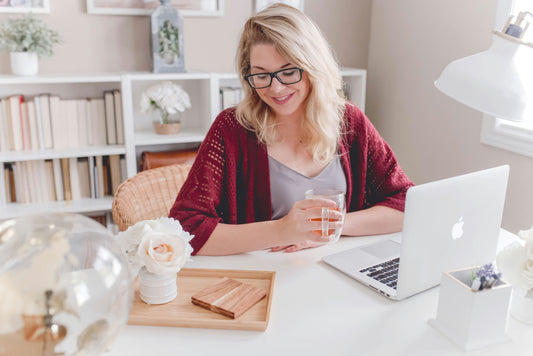 Woman working at desk with laptop demonstrating essential oils from Essential for Wellness
