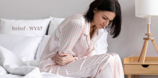 Woman in pink-striped pajamas clutching abdomen from menstrual pain