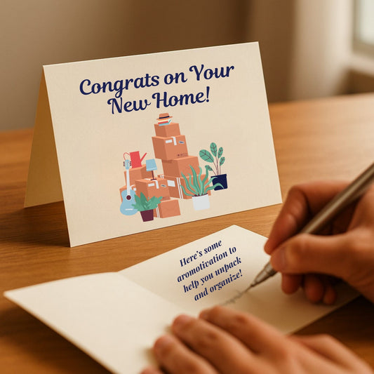 Congrats on your new home card for essential oil gift sets, featuring piles of boxes and plants and handwritten message from Essential for Wellness.